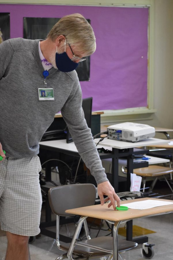 Math teacher Erik Running sets a green bracelet on a student desk to represent Cohort A.