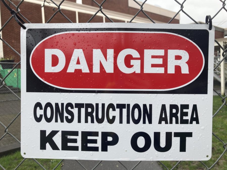 A sign on the chain-link fence marks a construction area near the gym.