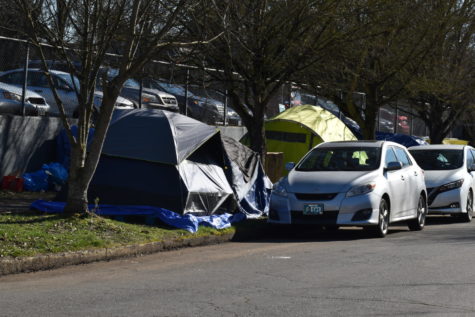 Tents sit on and near the sidewalk at a homeless camp behind the Cleveland staff parking lot on 25th Avenue.
