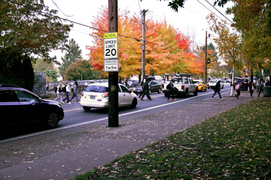 Students arrive from Bus 10 and cross the street in front of traffic just before the start of school Nov. 10. ODOT posted new signs around the school showing the new speed limit from 7 a.m. to 5 p.m.