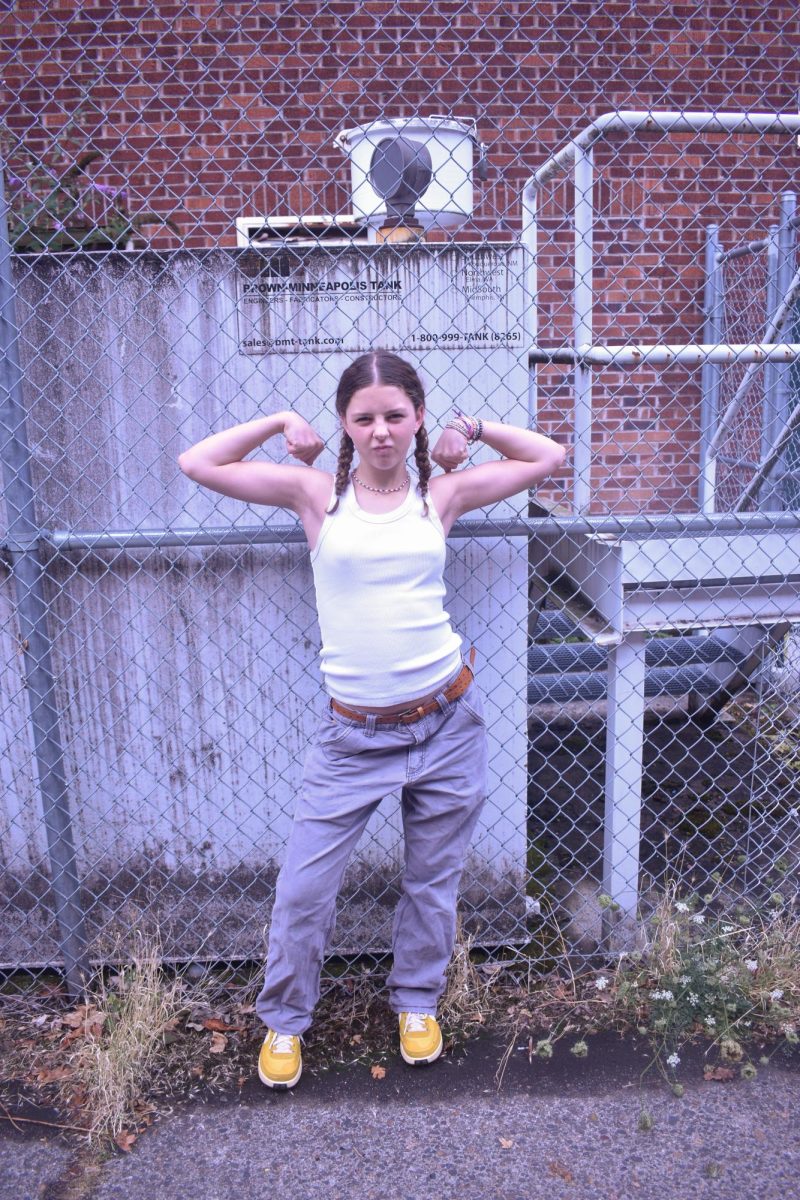 Wynnie Posedel wearing a white tank paired with gray pants and yellow shoes.