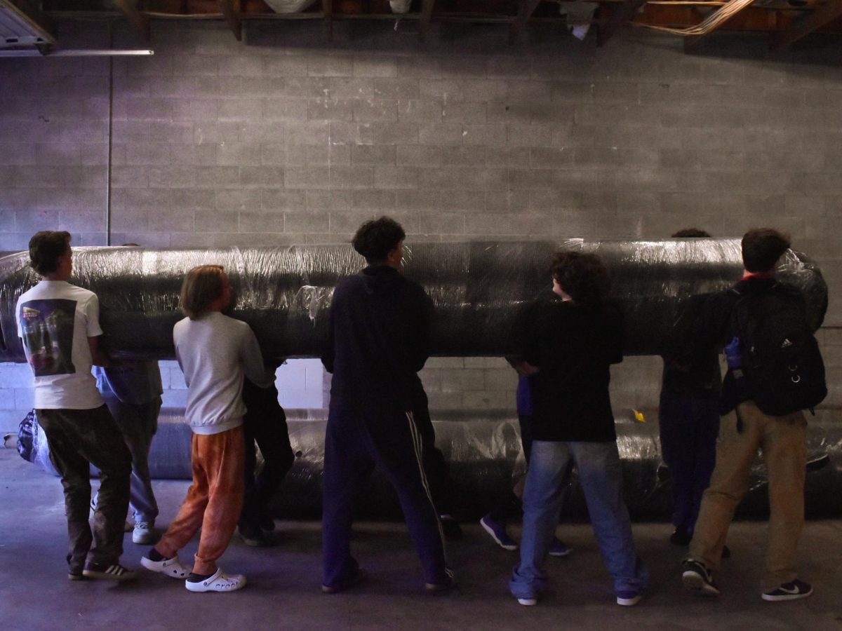 Baseball players work together to unload and set up mats of turf in the new facility. Natalie Benn photo.